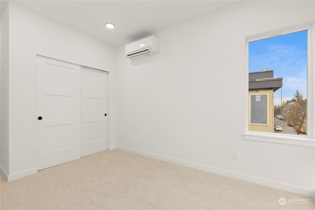 unfurnished bedroom featuring a wall mounted AC, a closet, and light colored carpet