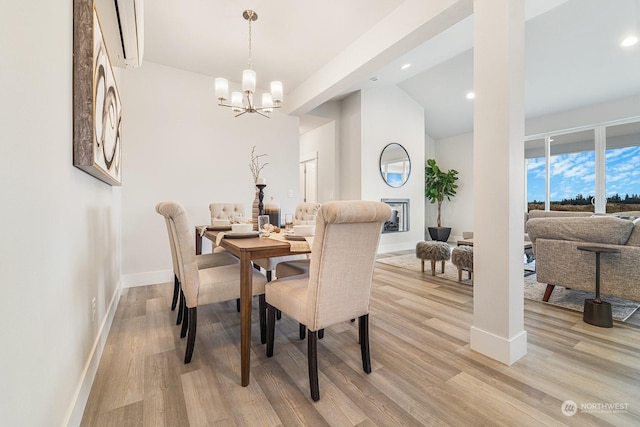 dining space featuring an AC wall unit, light hardwood / wood-style floors, lofted ceiling, and a notable chandelier