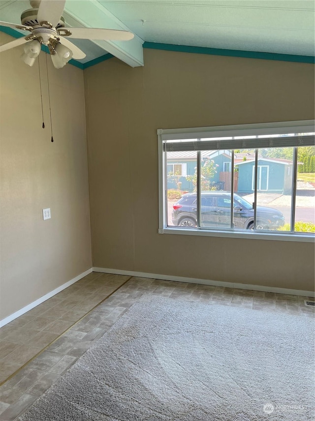 empty room featuring vaulted ceiling with beams and ceiling fan