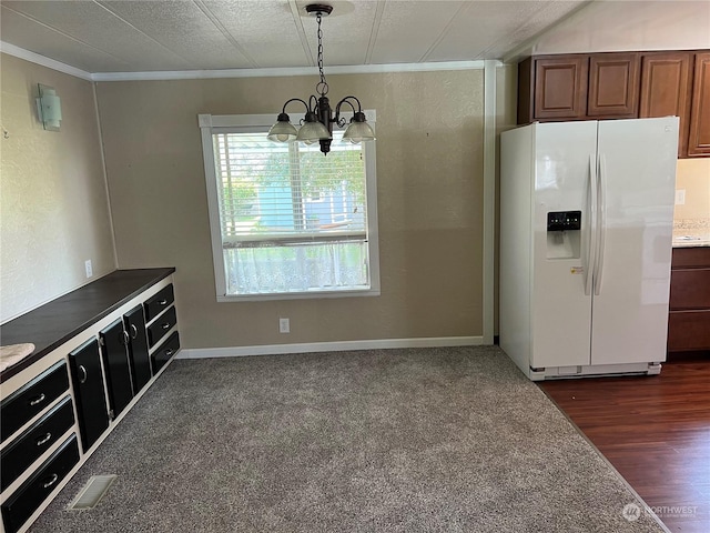 kitchen featuring white refrigerator with ice dispenser, dark wood-type flooring, an inviting chandelier, crown molding, and hanging light fixtures