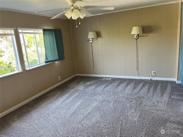 empty room with carpet, a textured ceiling, ceiling fan, and wood walls