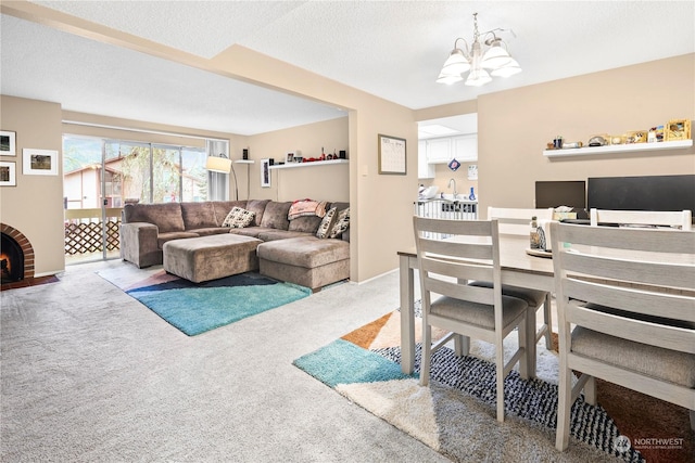 dining space with a textured ceiling, an inviting chandelier, a brick fireplace, and light carpet