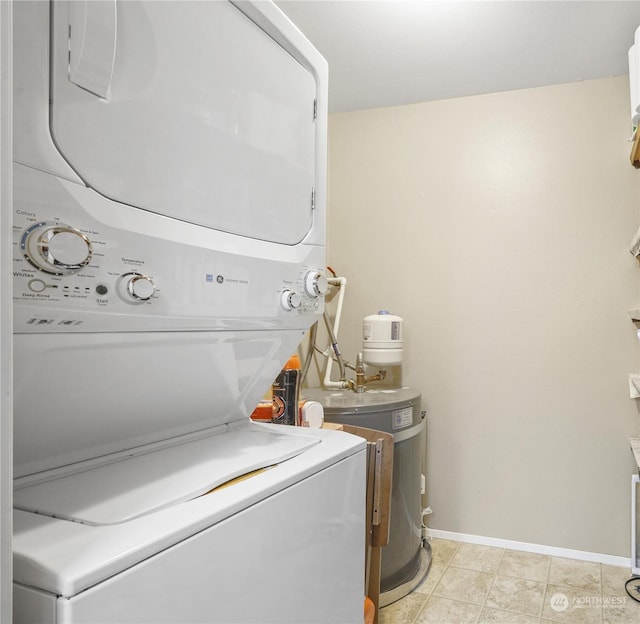 laundry area featuring light tile patterned floors, baseboards, stacked washer and dryer, and laundry area