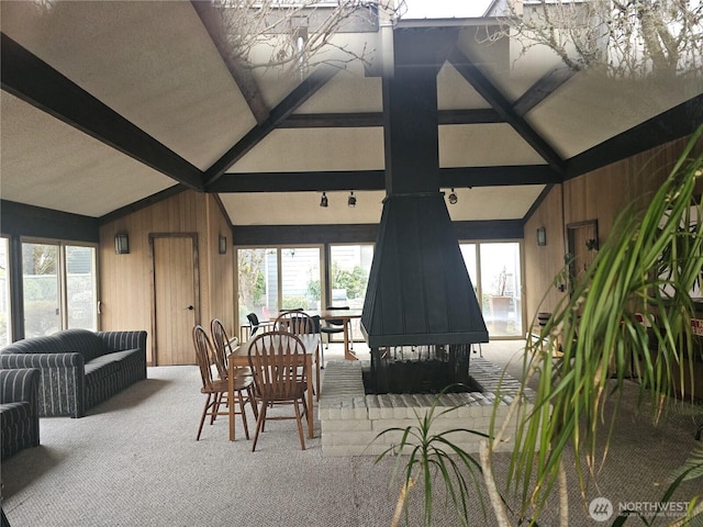 dining area with lofted ceiling with beams, wooden walls, and carpet