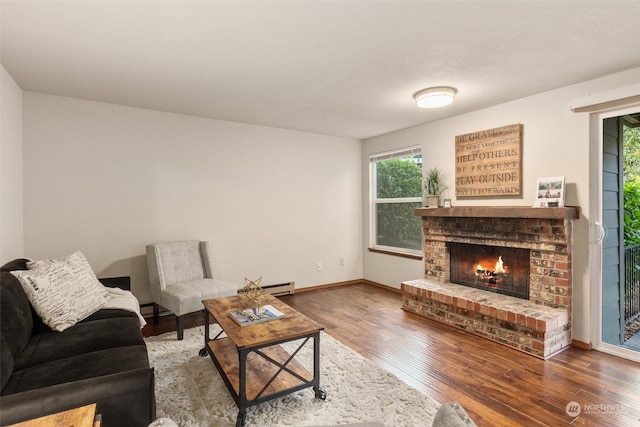 living room featuring a fireplace, hardwood / wood-style floors, and a baseboard heating unit