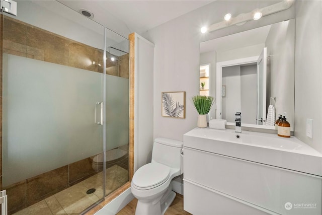 bathroom featuring a shower with door, vanity, and toilet