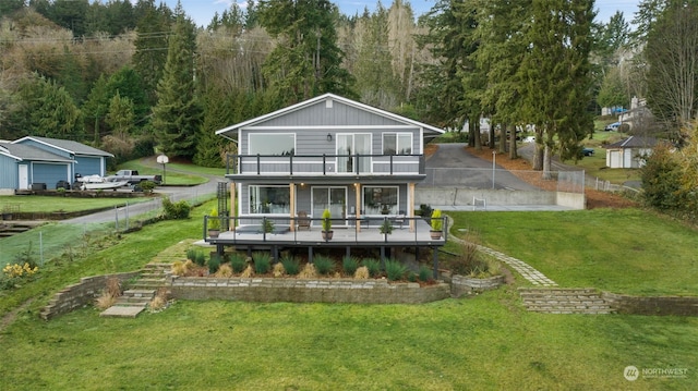 back of property with a yard, a balcony, and a deck