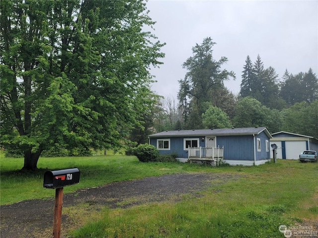 view of front of property featuring an outbuilding, a front lawn, a garage, and a deck