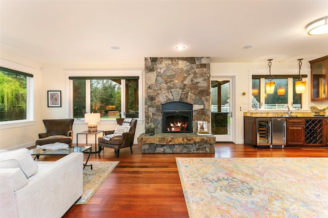 living room with dark hardwood / wood-style floors, wet bar, plenty of natural light, and a fireplace