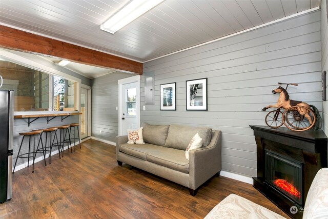 living room with wood walls, beamed ceiling, and dark wood-type flooring