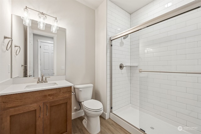 bathroom with walk in shower, vanity, toilet, and hardwood / wood-style floors