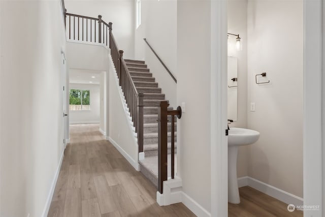 stairway with hardwood / wood-style floors and a high ceiling