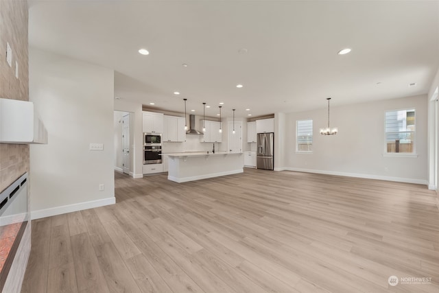 unfurnished living room with a notable chandelier, light hardwood / wood-style floors, and a tile fireplace