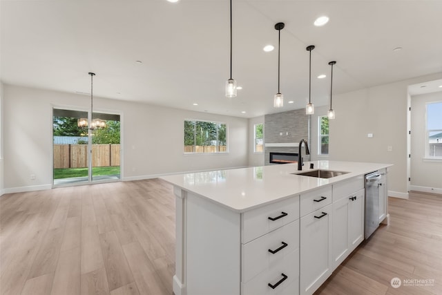 kitchen with decorative light fixtures, sink, and an island with sink