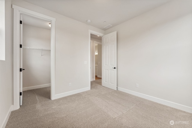 unfurnished bedroom with light carpet and a closet