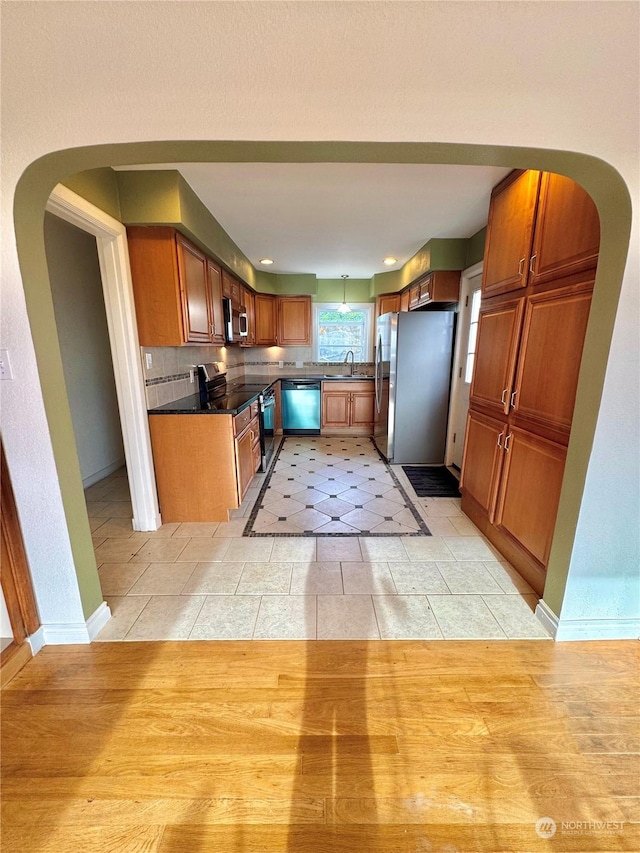 kitchen with decorative backsplash, light tile patterned floors, stainless steel appliances, and sink