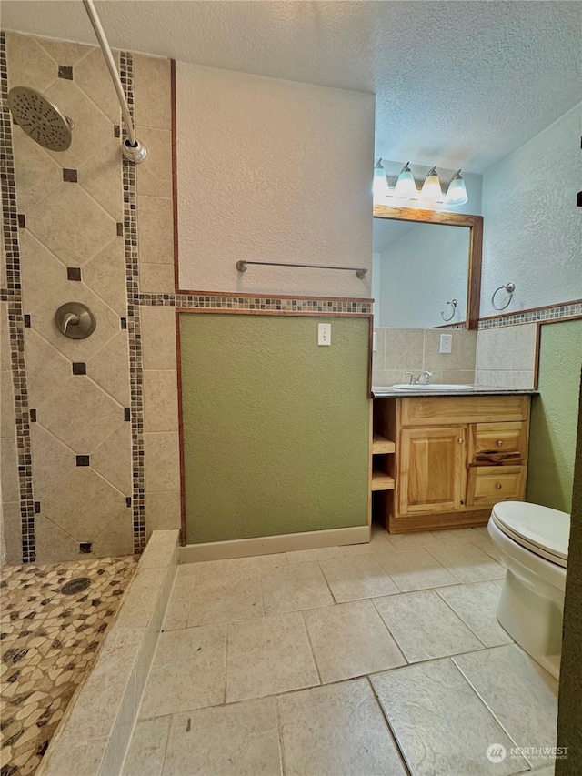 bathroom with tiled shower, vanity, a textured ceiling, and toilet