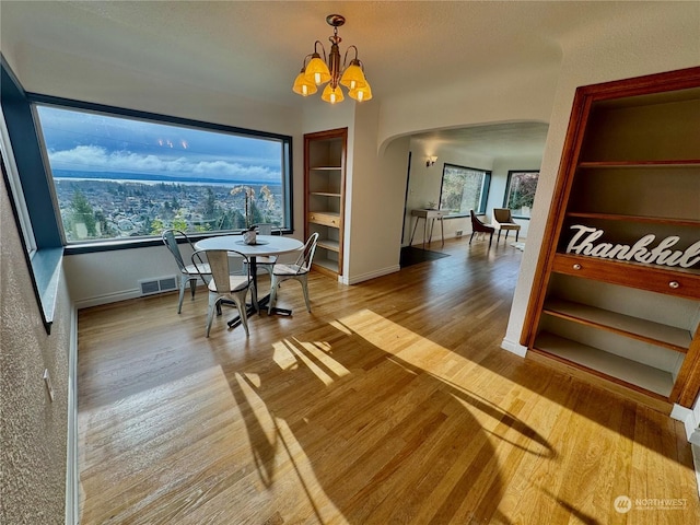 dining room featuring hardwood / wood-style floors, built in shelves, and an inviting chandelier