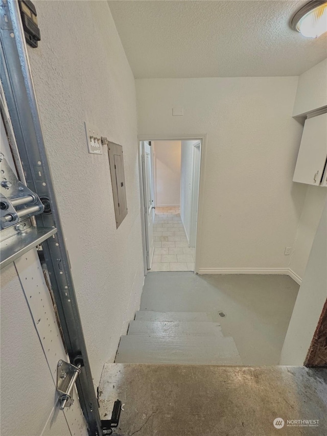 corridor with a textured ceiling and electric panel