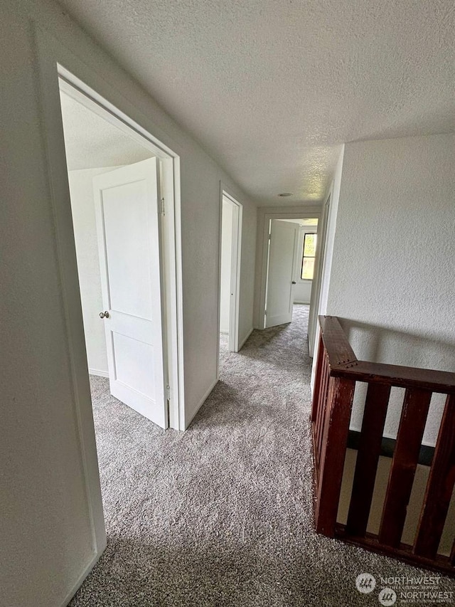 corridor featuring a textured ceiling and light carpet