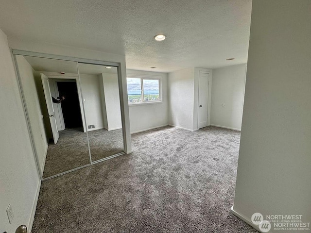 unfurnished bedroom with a closet, dark carpet, and a textured ceiling