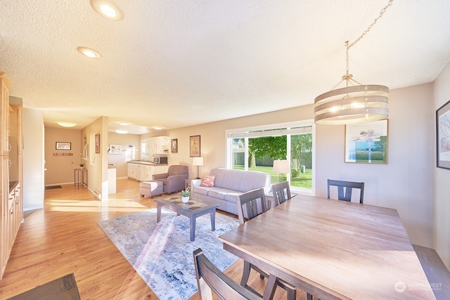 living room featuring a textured ceiling, a notable chandelier, and light wood-type flooring