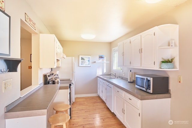 kitchen featuring white cabinets, sink, stainless steel appliances, and light hardwood / wood-style flooring