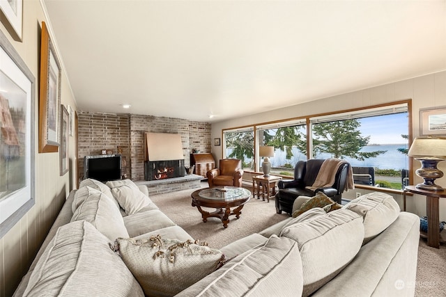 living room with carpet, a water view, and a brick fireplace