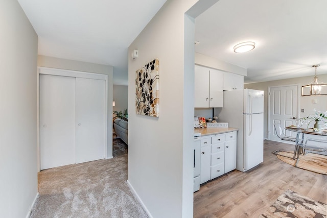 kitchen featuring pendant lighting, range, white fridge, white cabinetry, and a chandelier