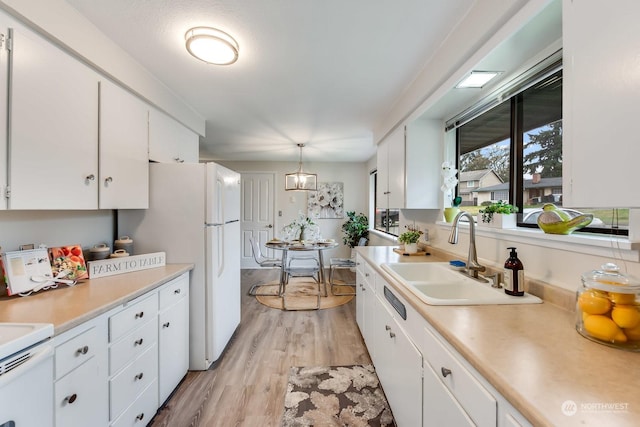 kitchen with decorative light fixtures, light hardwood / wood-style floors, white cabinetry, and sink