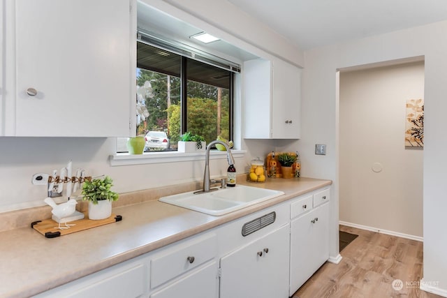 kitchen featuring white cabinets, sink, and light hardwood / wood-style flooring