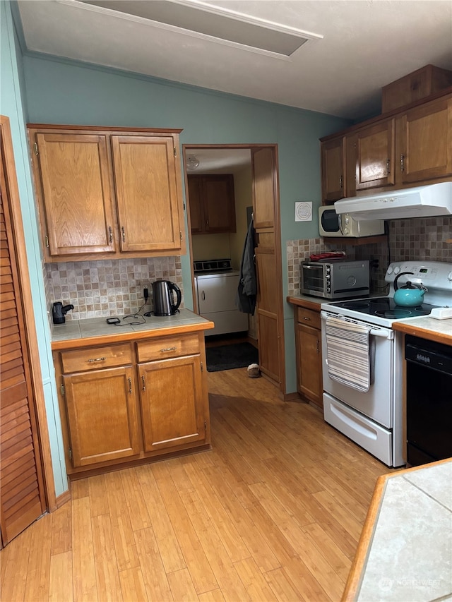 kitchen with vaulted ceiling, black dishwasher, tasteful backsplash, white range oven, and washer / clothes dryer