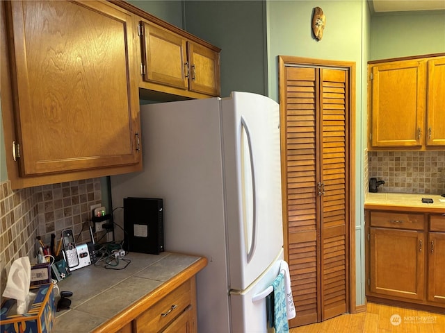 kitchen featuring backsplash, light wood-type flooring, and tile counters