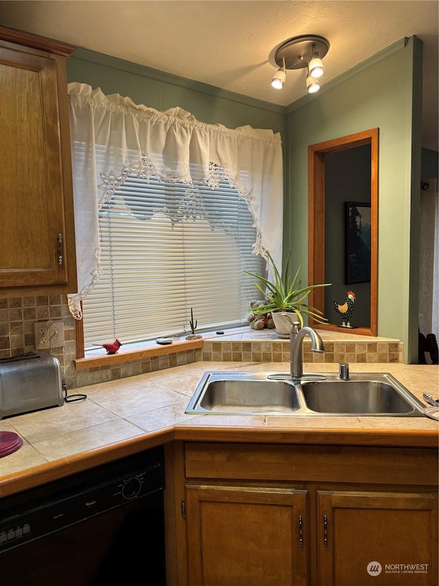 kitchen with sink, tasteful backsplash, black dishwasher, and tile counters