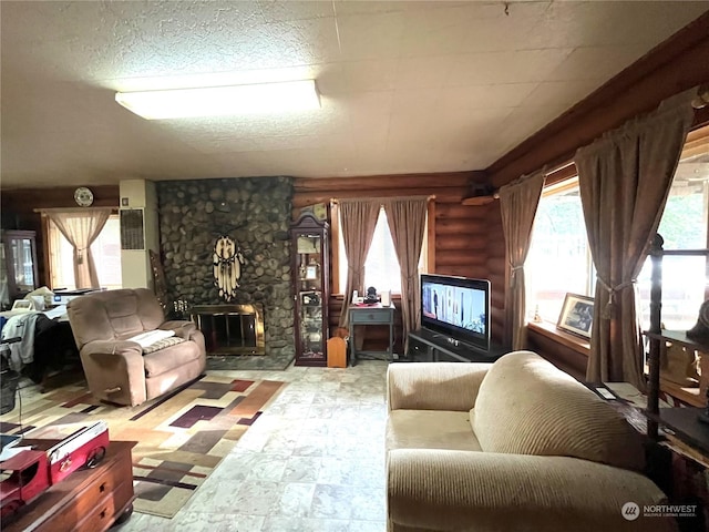 living room with a stone fireplace, log walls, and a textured ceiling