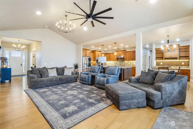 living room featuring light wood-type flooring, vaulted ceiling, and ceiling fan with notable chandelier