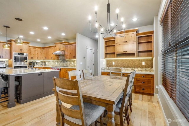 dining space with light hardwood / wood-style floors, a chandelier, and sink