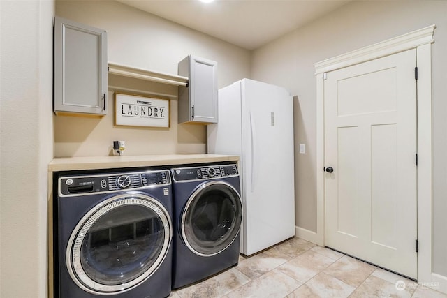 clothes washing area with cabinets and washing machine and clothes dryer