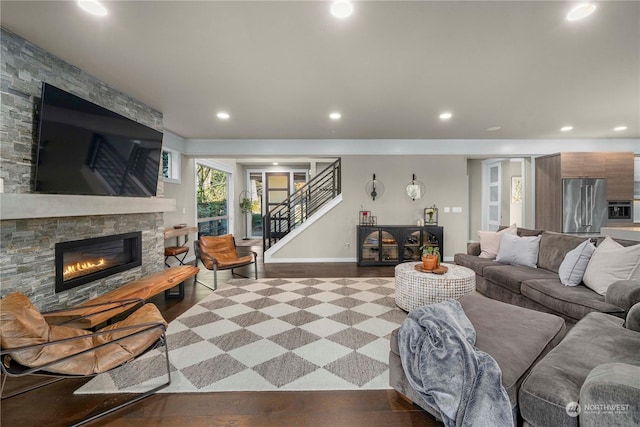 living room with wood-type flooring and a stone fireplace