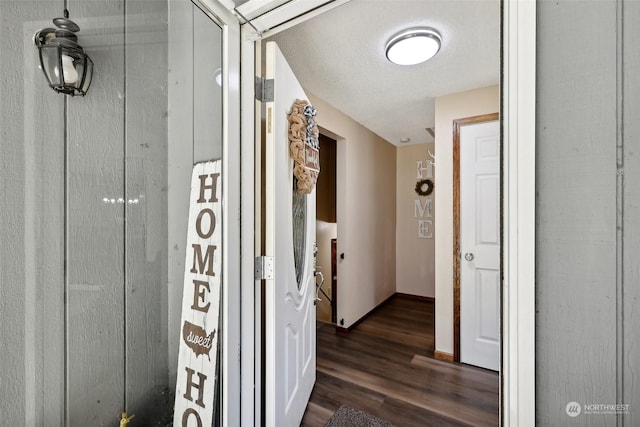 corridor with dark hardwood / wood-style flooring and a textured ceiling