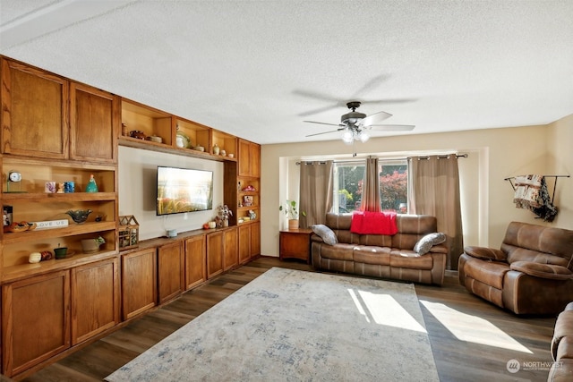 living room with a textured ceiling, ceiling fan, and dark wood-type flooring