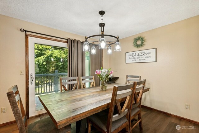 dining area with dark hardwood / wood-style flooring, a textured ceiling, and a chandelier