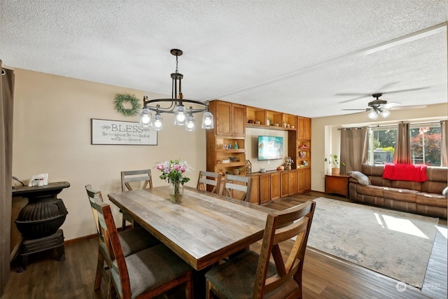 dining space with a textured ceiling, ceiling fan with notable chandelier, and dark wood-type flooring