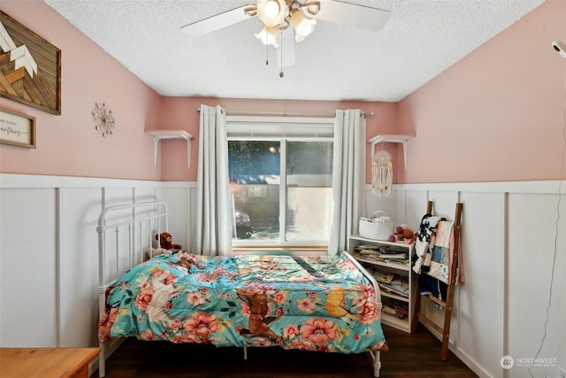 bedroom with ceiling fan, dark wood-type flooring, and a textured ceiling