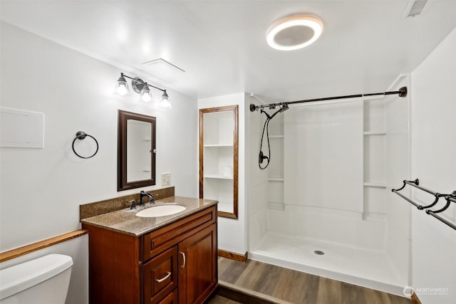 bathroom with hardwood / wood-style flooring, vanity, toilet, and walk in shower