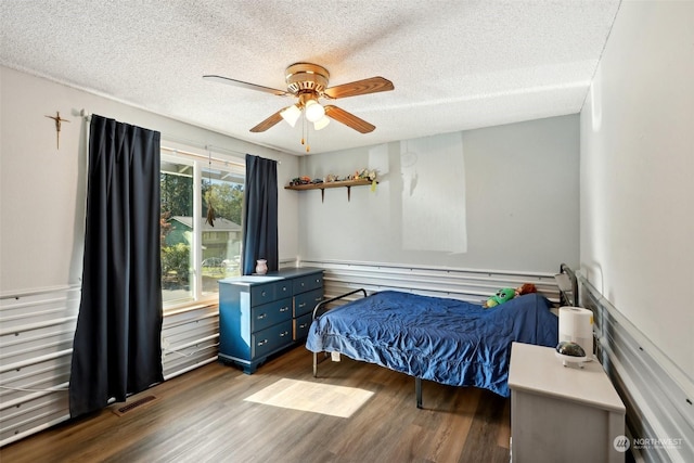 bedroom featuring ceiling fan, dark hardwood / wood-style flooring, and a textured ceiling