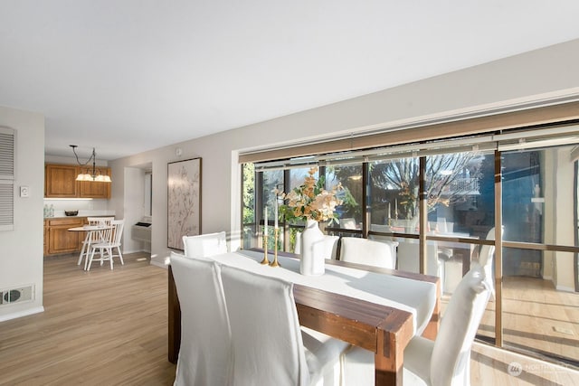 dining space with an inviting chandelier and light hardwood / wood-style floors