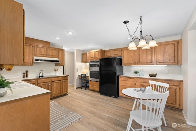 kitchen featuring hanging light fixtures, an inviting chandelier, light hardwood / wood-style floors, and black appliances