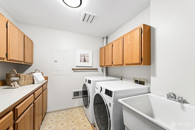 washroom with sink, electric panel, cabinets, and washing machine and clothes dryer