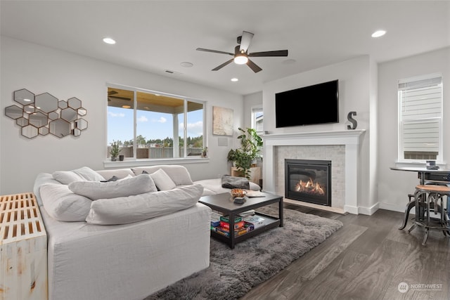 living room with ceiling fan, dark hardwood / wood-style flooring, and a tiled fireplace